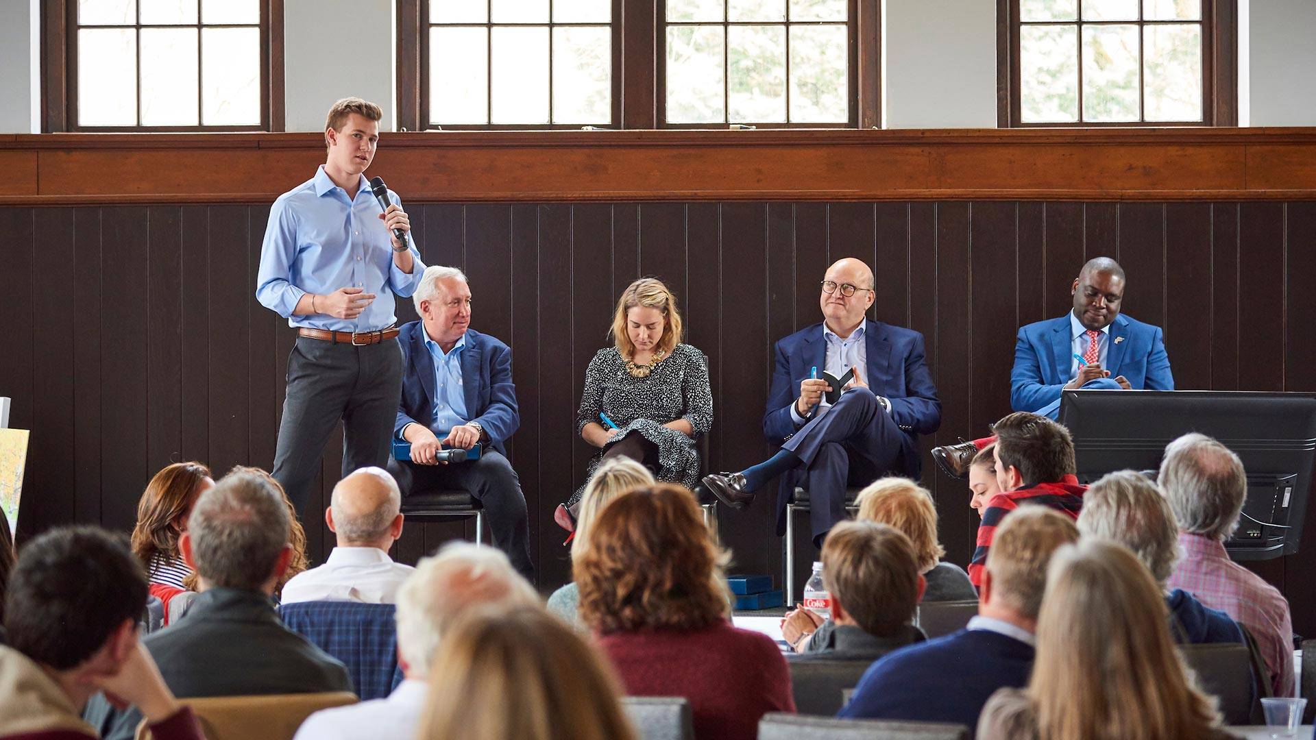 Student speaking onstage with panel